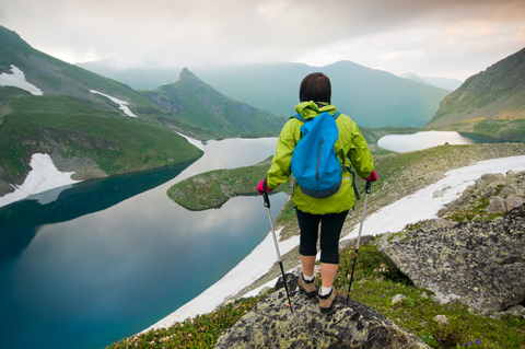 Kvinna vandrar med stavar i berg